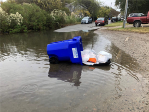 Recycling bin filled with trash falls over into flood waters in Norfolk. 